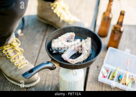 Braten zwei Fische steakes am Brenner beim Picknick mit Bier und Angeln geht im Freien Stockfoto