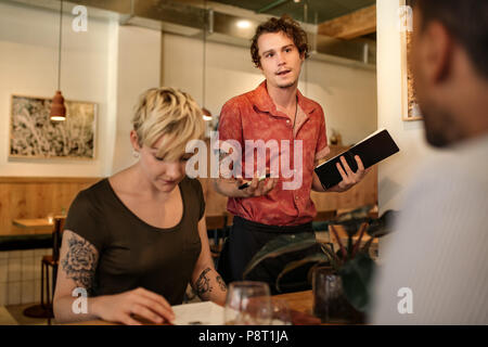 Kellner im Gespräch mit dem Kunden in einem Bistro Tisch Stockfoto