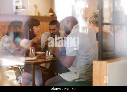 Vielfältige Gruppe von jungen Freunden zusammen essen in einem Bistro Stockfoto