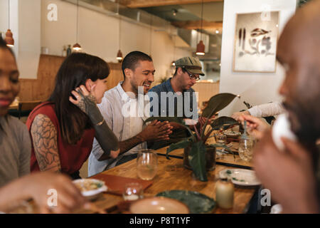 Diverse junge Freunde Spaß haben zusammen über ein Bistro Abendessen Stockfoto