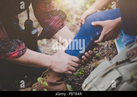 Asiatische junge Paar Reisende zu wandern Knöchelverletzung auf grünem Hintergrund, Wandern Konzept. Stockfoto