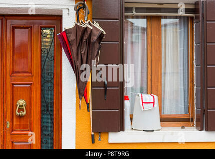 Braune und Rote Schirme außerhalb Buntes Haus Burano Italien Stockfoto