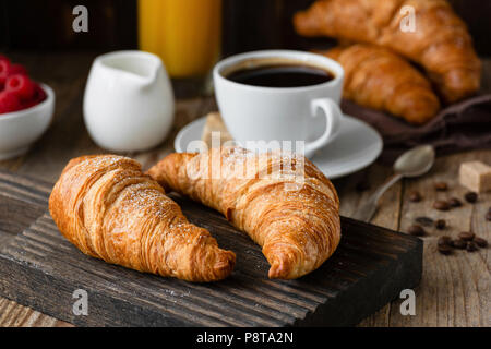 Frühstück mit Croissants, Kaffee, Orangensaft und Beeren auf Holztisch. Detailansicht, selektiver Fokus Stockfoto