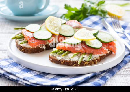 Lachs Sandwiches mit Spargel, Frischkäse und Gurke auf weiße Platte. Gourmet Snacks, Mittag- oder Vorspeise. Detailansicht, selektiver Fokus Stockfoto