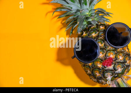 Nahaufnahme reife rote Lippe Ananas mit Sonnenbrille auf gelben Hintergrund, Kopie Raum Stockfoto