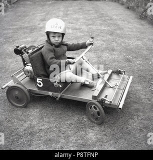 1967, im Freien in einem Garten ein kleiner Junge auf einer kleinen 1-Sitzer nach Hause sitzen - Eingebaute motorisierte Go-Kart, England, UK. Stockfoto