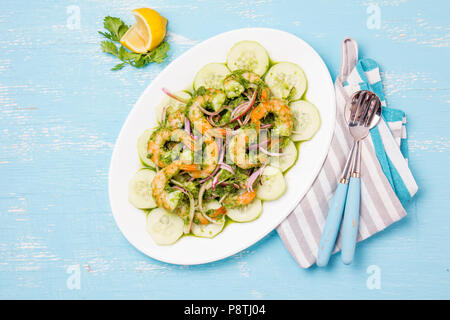 Mexikanische Küche. Aguachile de Camaron. Garnelen aguachile. Garnelen eviche cebiche mit Gurke, Zitrone und violette Zwiebel. Ansicht von oben, blauen Hintergrund. Stockfoto