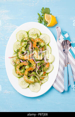 Mexikanische Küche. Aguachile de Camaron. Garnelen aguachile. Garnelen eviche cebiche mit Gurke, Zitrone und violette Zwiebel. Ansicht von oben, blauen Hintergrund. Stockfoto