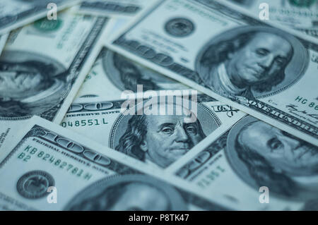 Einen Hintergrund von hundert Dollar auf dem Tisch verteilt. Konzentrieren Sie sich auf eine Rechnung. Stockfoto