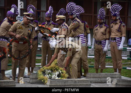 Srinagar, Kashmir. 13. Juli 2018. Jammu und Kaschmir Polizisten setzen Kranz auf einem Grab auf dem Friedhof der Märtyrer in Srinagar. Juli 13 ist als Märtyrer' Tag in Erinnerung an den Tag beobachtet, wenn Hinduistische König der Region bestellt mehr als 20 kaschmirische Muslime in einem Angebot, einem Aufstand 1931, ausgeführt. Credit: SOPA Images Limited/Alamy leben Nachrichten Stockfoto