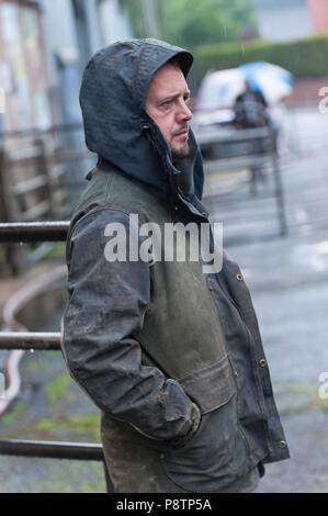 Builth Wells, Powys, UK. 13. Juli 2018. Schafhalter kommen für den Regen mit regenjacken bei der wöchentlichen Schafmarkt in Builth Wells, Powys, Wales, UK vorbereitet. © Graham M. Lawrence/Alamy Leben Nachrichten. Stockfoto