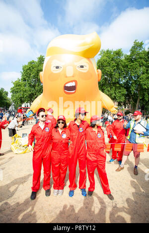 London/Großbritannien - 13. Juli 2018: Donald Trump Besuch in England ist mit Protesten und ein Luftschiff über das Londoner Parlament Platz fliegen. Der Protest Team stellt für die Kameras mit Verärgerten Trump Baby im Hintergrund. Stockfoto