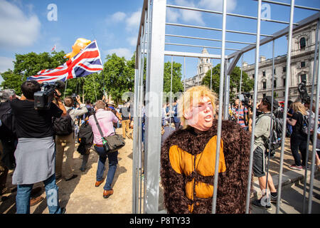 London/Großbritannien - 13. Juli 2018: Donald Trump Besuch in England ist mit Protesten und ein Luftschiff über das Londoner Parlament Platz fliegen. Ein Mann in einem Gorilla Anzüge gekleidet ist in einem Käfig Tragen eines Trumpf-Maske. Stockfoto