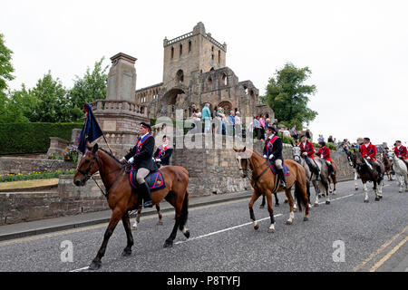 JEDBURGH, Schottland - Juli 13: Jethart Callant's Festival - Festival Tag Jethart Callant 2018 Nick Arnold (72Nd Jethart Callant) führt die montiert Kavalkade von Pferden zusammen mit Linken Mann Gary Hogg und Rechter Mann Brodie Irvine, gefolgt vom ehemaligen Boten während der Jethart Callant's Festival, ein jährliches Festival, Teil der schottischen Grenze gemeinsame Reiten Saison. Festival Tag am Juli 13, 2018 in Jedburgh. Wie Sie verlassen die Stadt auf der morgens zeremoniellen rideout, vorbei an den Ruinen der Jedburgh Abbey und die Städte War Memorial (Foto von Rob Grau/Freiberufler) Stockfoto