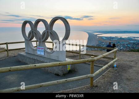 Farmhouse, Isle of Portland, Dorset, Großbritannien. 13. Juli 2018. Ein Portland Stein Olympische Ringe Skulptur für die Olympischen Spiele 2012 in London erstellt wurde an der Portland Höhen eingezäunt auf der Isle of Portland in Dorset wegen Sicherheitsbedenken wegen Besucher klettern auf es zusammenbrechen kann. Die sculpure wurde ursprünglich an Wemouth Bahnhof während der Segel-events gelegen und an seinen aktuellen Standort umgezogen nach den Olympischen Spielen 2012 beendete. Foto: Graham Jagd-/Alamy leben Nachrichten Stockfoto