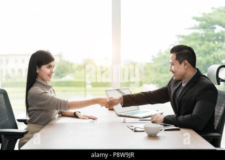 Paar asiatische Geschäftsleute mit Freizeitkleidung im Gespräch mit glücklich und zitternder Hand in modernen Büros oder im Café. Business-Erfolg-Konzept