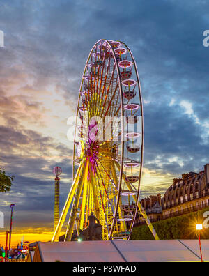 Die beliebten Symbol Riesenrad in Paris Frankreichs bei Sonnenuntergang in der Nähe von Louvre Museum mit historischen Gebäude im Hintergrund. Vertikale erschossen. Stockfoto