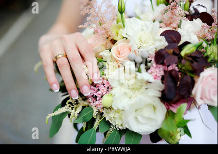 Der Braut Hände mit einem ehering am Finger und Hochzeit Blumen Stockfoto