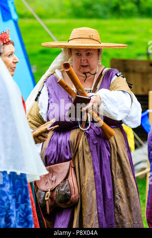 Lebendige Geschichte Mittelalter reenactment Event. Reife Frau, 50 Jahre, in den mittelalterlichen Minnesänger Kostüm gekleidet, und halten zwei holzflöten in ihrer Hand. Stockfoto