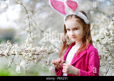 Adorable kleinen Mädchen in Kirschblüten Garten auf schönen Frühlingstag Stockfoto