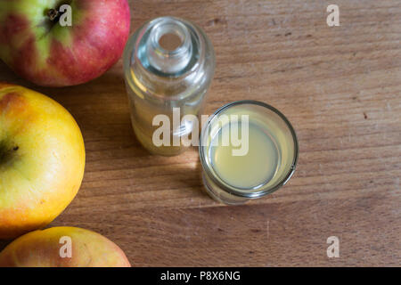 Stärkung der Immunabwehr, Haut die Klärung, detoxing natürlicher Apfelessig auf Holztisch mit reife Äpfel als Dekoration Stockfoto