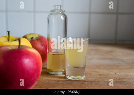 Stärkung der Immunabwehr, Haut die Klärung, detoxing natürlicher Apfelessig auf hölzernen Küchentisch mit reife Äpfel als Dekoration Stockfoto