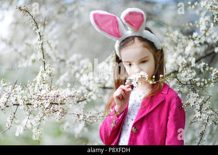 Adorable kleinen Mädchen in Kirschblüten Garten auf schönen Frühlingstag Stockfoto