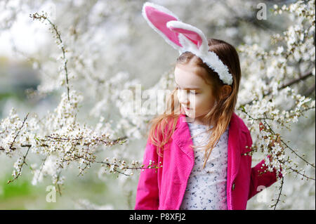 Adorable kleinen Mädchen in Kirschblüten Garten auf schönen Frühlingstag Stockfoto