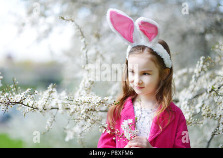 Adorable kleinen Mädchen in Kirschblüten Garten auf schönen Frühlingstag Stockfoto