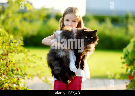 Süße kleine Mädchen, dass riesige schwarze Katze im Freien Stockfoto