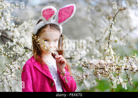 Adorable kleinen Mädchen in Kirschblüten Garten auf schönen Frühlingstag Stockfoto