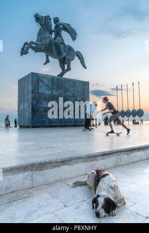 Skateboarder spielen und streunenden Hund schlafen von Alexander Statue des Großen auf Thessaloniki Waterfront, Mazedonien, Nordgriechenland Stockfoto