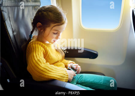 Entzückende kleine Mädchen mit dem Flugzeug reisen. Kind Flugzeug Fenster sitzen und nach draußen. Stockfoto