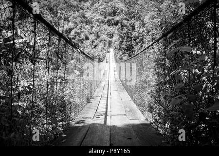 Hölzerne Hängebrücke über den Fluss in Panajachel, Guatemala, Mittelamerika in Schwarz und Weiß Stockfoto