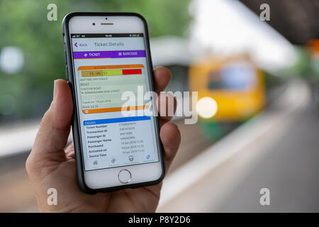 BIRMINGHAM, Großbritannien - 19 Juni, 2018: Close-up ein iPhone 6 angezeigte eine elektronische Fahrkarte, mit einem Zug am Bahnsteig hinter sich. Stockfoto