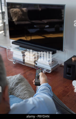 Mann wechseln der Kanäle beim Fernsehen im Wohnzimmer Stockfoto