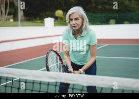 Ältere Frau spielt Tennis im Tennis Court Stockfoto