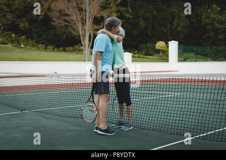 Senior Paar umarmen in Tennisplatz Stockfoto