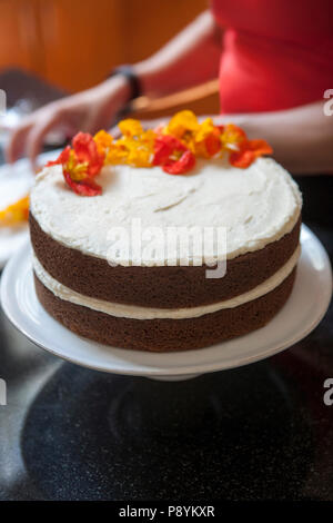 Essbare Blüten auf zweischichtigen Spice Kuchen mit Buttercream Vereisung Stockfoto