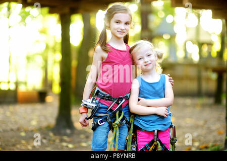 Zwei Entzückende kleine Mädchen genießen ihre Zeit im Klettern Adventure Park an warmen und sonnigen Sommer. Sommer Aktivitäten für junge Kinder. Kinder havi Stockfoto