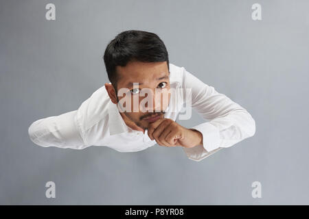 Denken asiatische junge Mann auf grauem Hintergrund über der oberen Ansicht isoliert Stockfoto