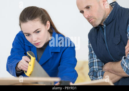 Junge weibliche Auszubildende Lernen von Hand Sägen Stockfoto