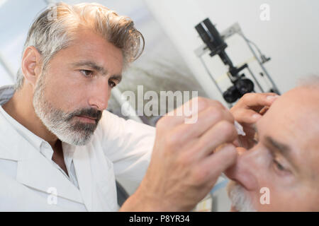 Arzt tropfen Augentropfen zu Patient Stockfoto