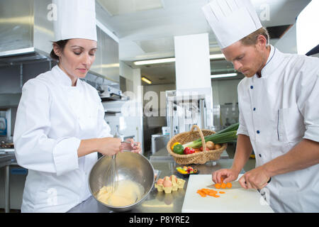 Zwei Köche garnieren Mahlzeit auf Zähler in der gewerblichen Küche Stockfoto