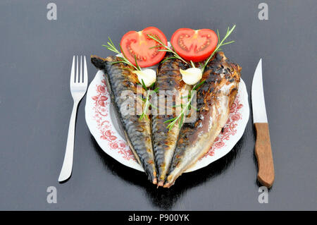 Gegrillter Fisch in eine weiße Platte mit Tomaten und Zwiebeln Stockfoto