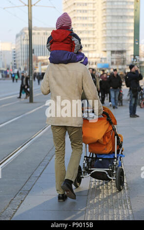 Berlin, Deutschland, Mensch sein Kind auf den Schultern und schiebt einen Kinderwagen Stockfoto