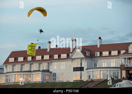 Ein Greenpeace-Protestler, der ein Ultraleichtflugzeug fliegt, fährt kurz nach der Ankunft des US-Präsidenten im Hotel über Donald Trumps Resort in Turnberry, South Ayrshire, mit einem Spruchband mit der Aufschrift "Trump: Weit unter Par". Stockfoto