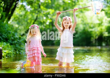 Zwei süße kleine Schwestern spielen in einem Fluss fang Gummienten mit ihren Scoop - Netze an warmen und sonnigen Sommer Tag Stockfoto