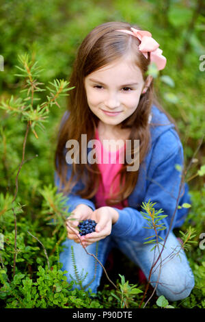 Süße kleine Mädchen pflücken Heidelbeeren in den Wäldern auf schönen Sommertag Stockfoto