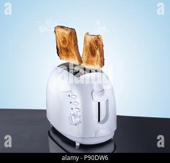 Toaster zusammengesetzten Bild und Brot, Fliegen und springen Brot aus einem elektrischen Toaster, blauen Hintergrund und reflektierende Oberfläche gekocht Stockfoto